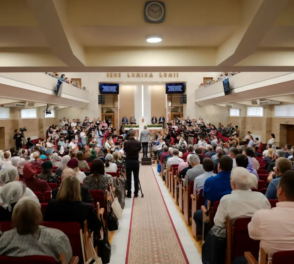Sala Bisericii Elim plină, văzută de pe culoarul din mijloc, într-o duminică